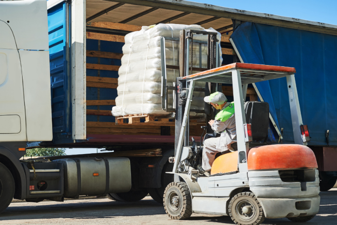Forklift loading palletized freight into a truck trailer