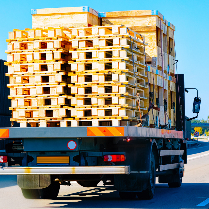 Flatbed truck loaded with stacks of wooden pallets