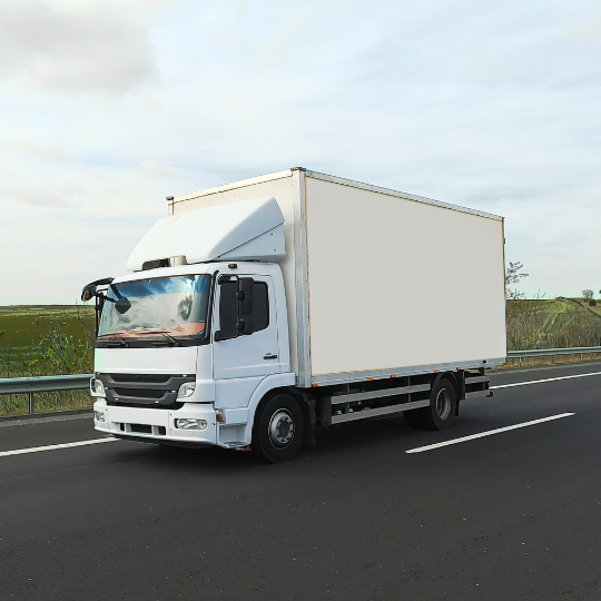 White refrigerated box truck driving on a highway