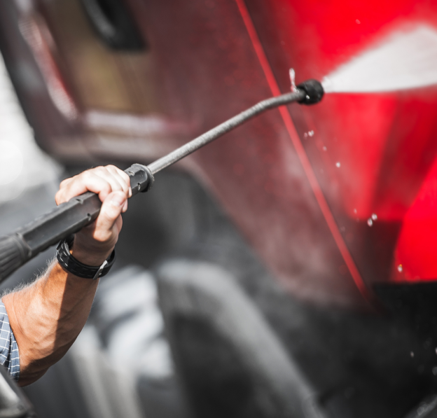 Worker pressure-washing a truck trailer
