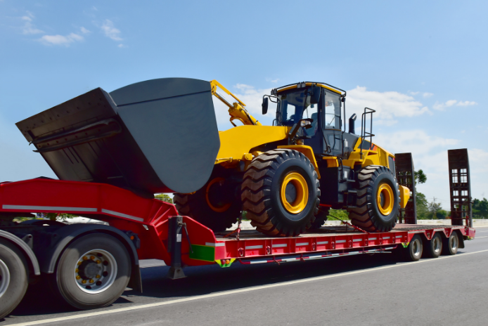 Yellow wheel loader loaded on a red lowboy trailer