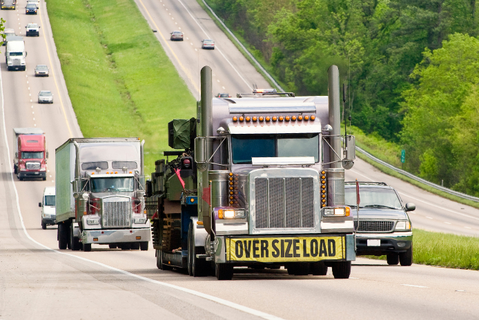 Semi truck with an Oversize Load sign hauling equipment on an interstate
