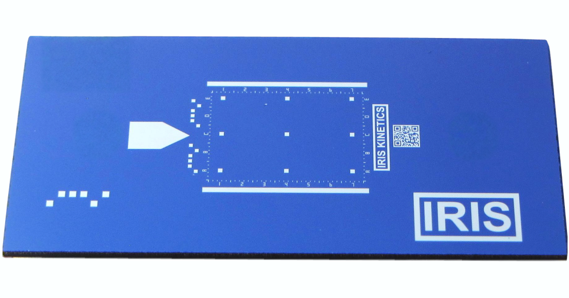 An IRIS chip, photographed: a blue dual-layer silicon chip, 8 by 16 mm, with an alignment arrow, a printed scale grid, a QR code and the IRIS mark.