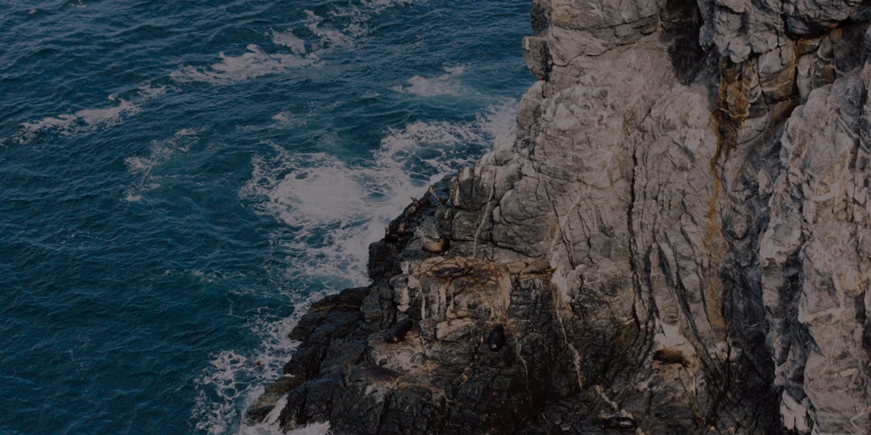 Waves crashing against dark rocky cliffs on the Baja coast
