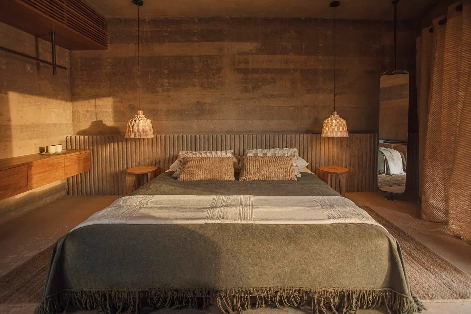 Suite bedroom with earthen walls, rattan lamps and linen bedding