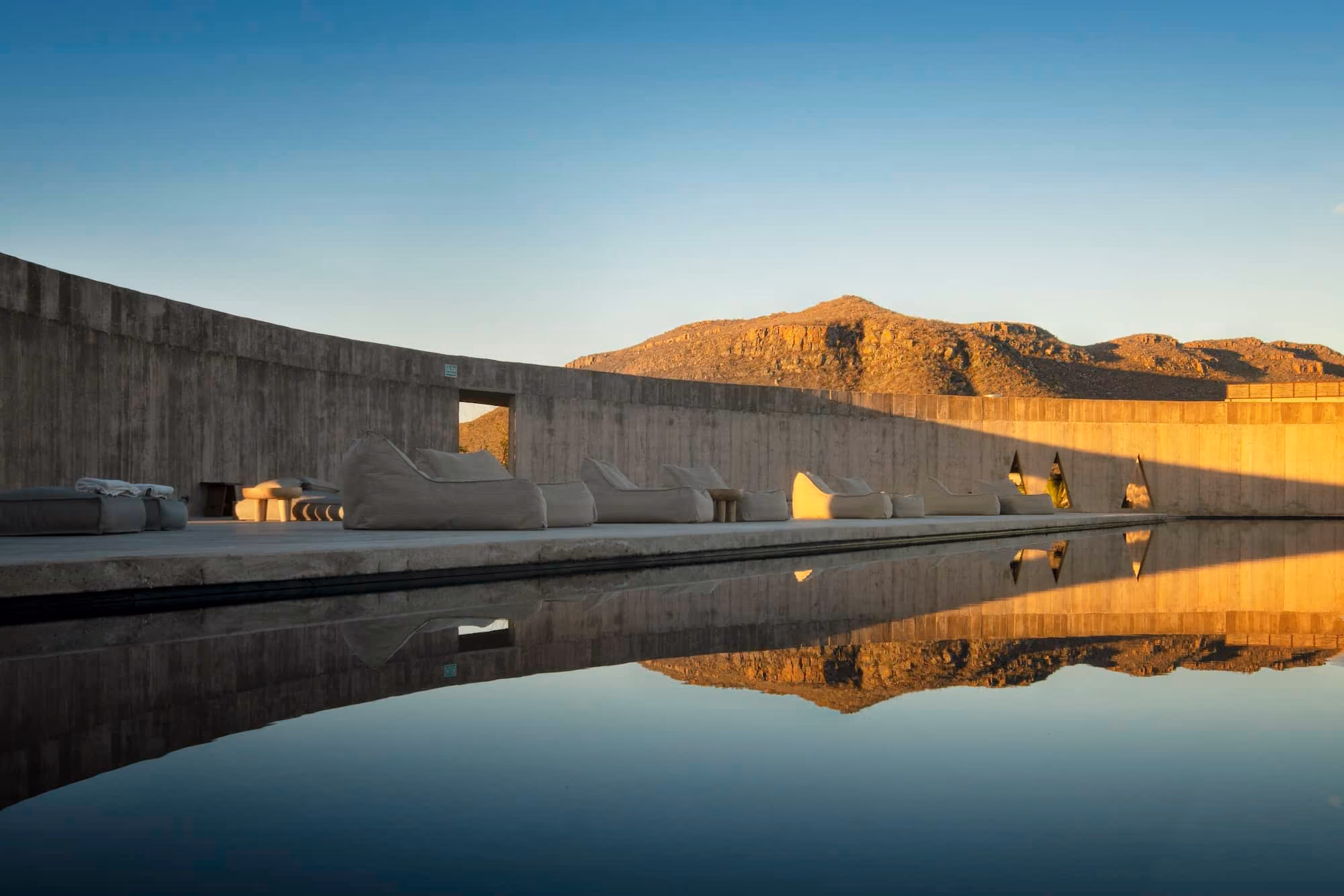 Infinity pool reflecting desert mountains at sunset