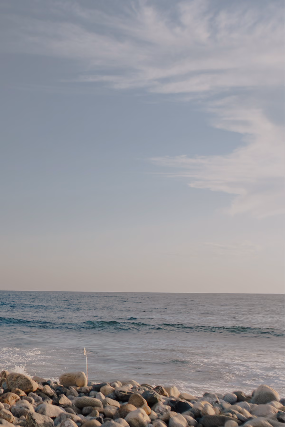 Pebble beach and calm Pacific Ocean under a soft sky