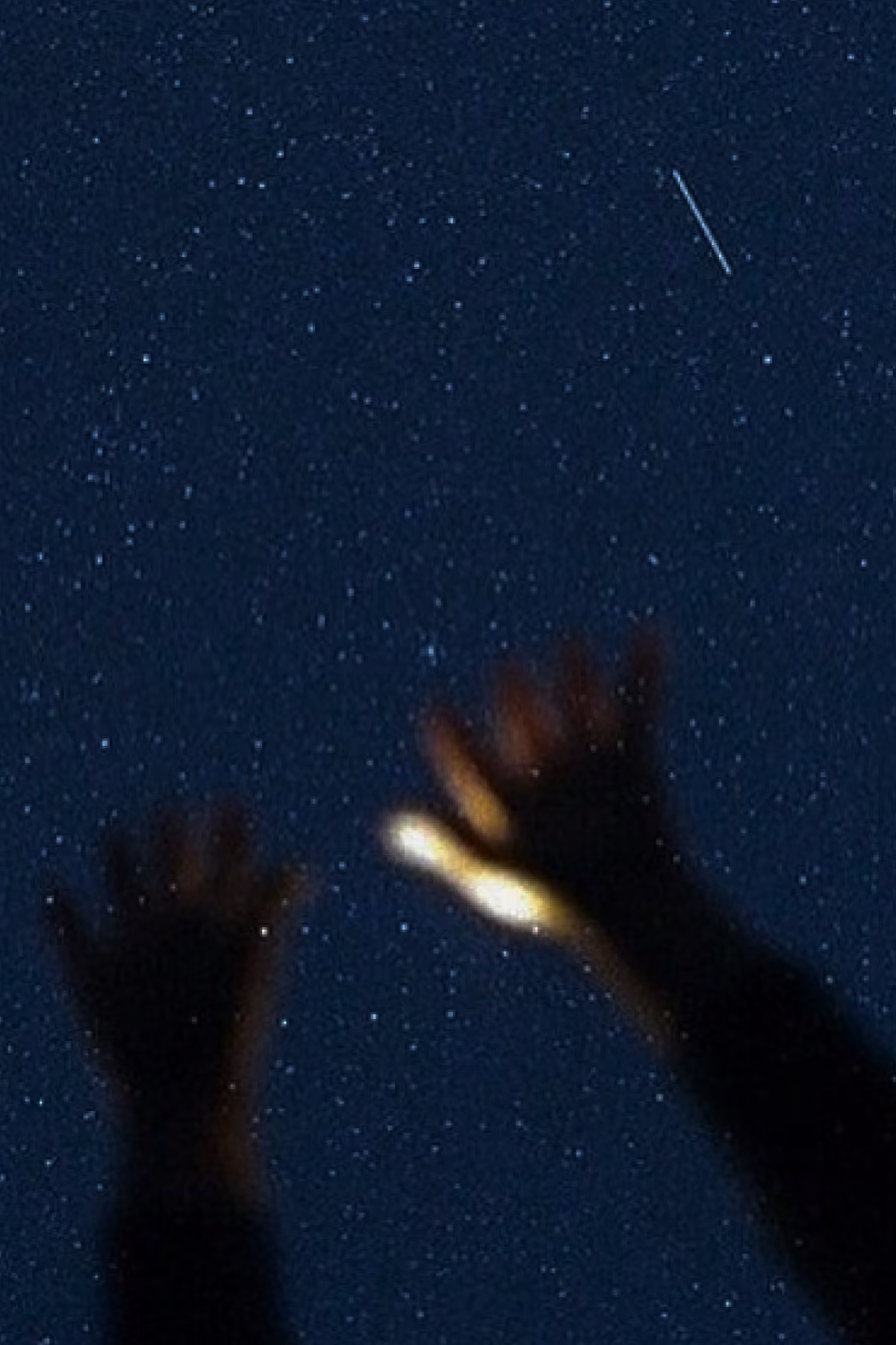 Hands raised toward a star-filled night sky