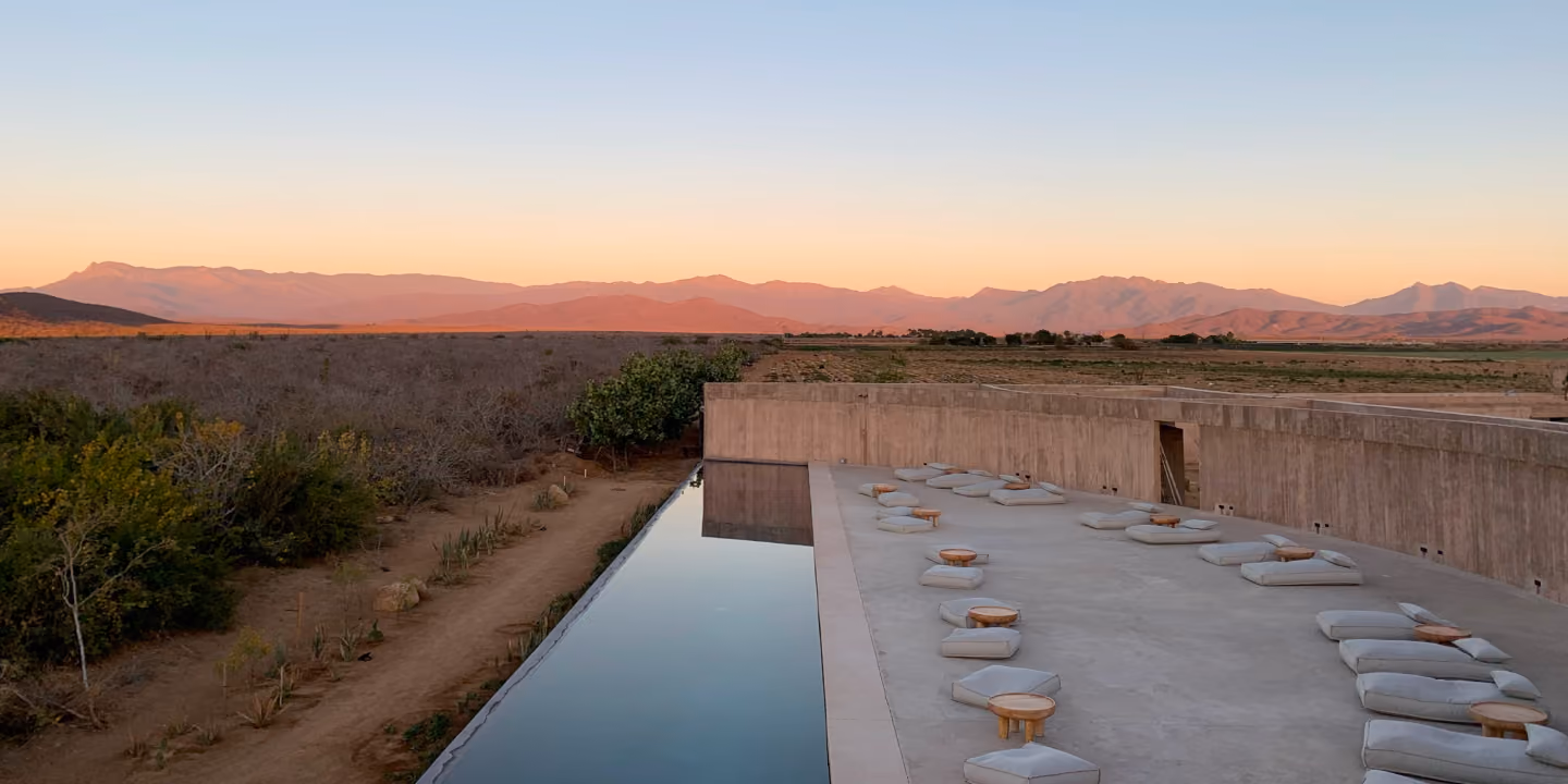 Long reflecting pool and seating facing desert mountains at dusk