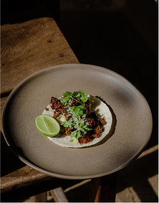 Taco with herbs and lime on a ceramic plate