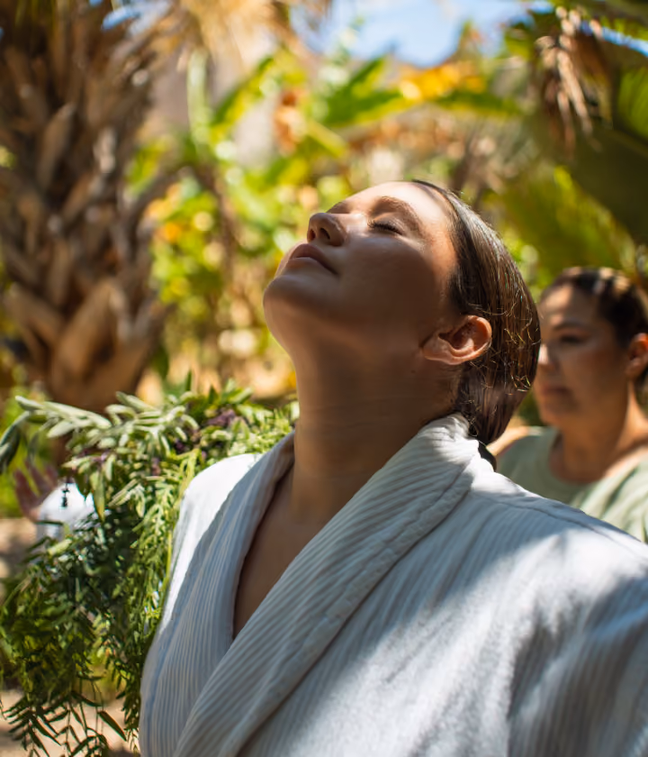 Guest in a robe relaxing in the garden at Ojo de Agua spa