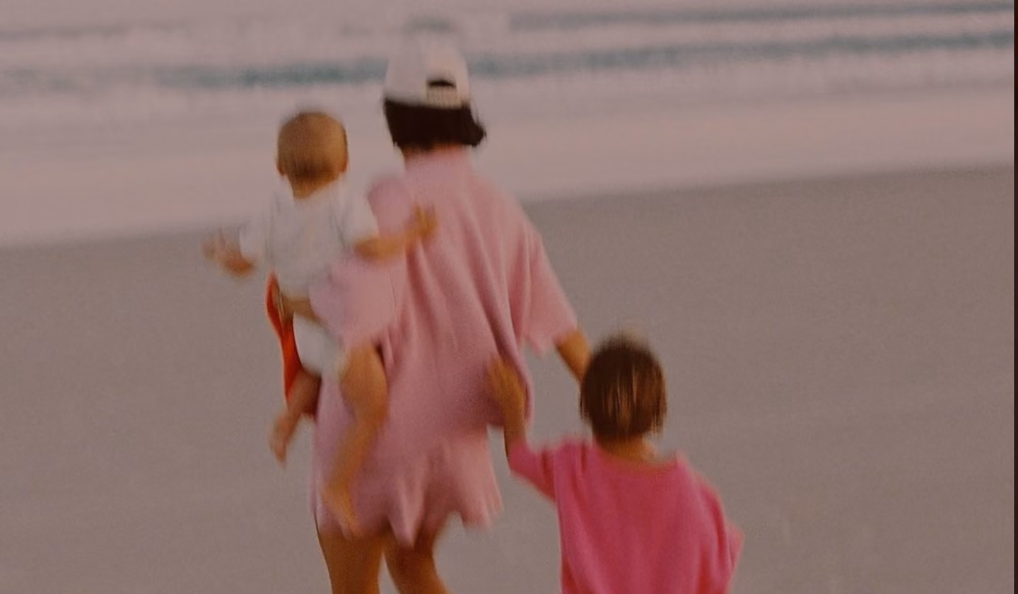 Mother walking with two young children on the beach