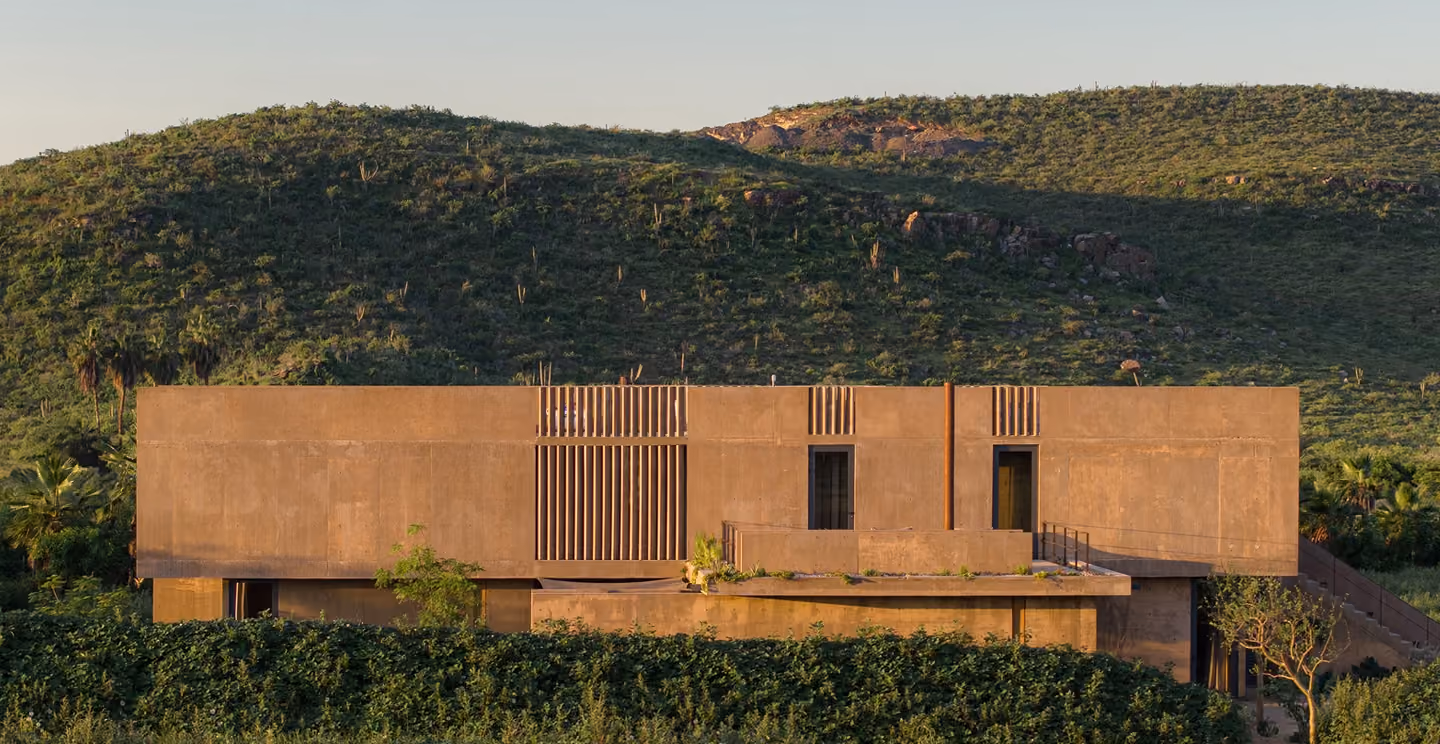 Paradero Homes residence nestled into green hillside at golden hour