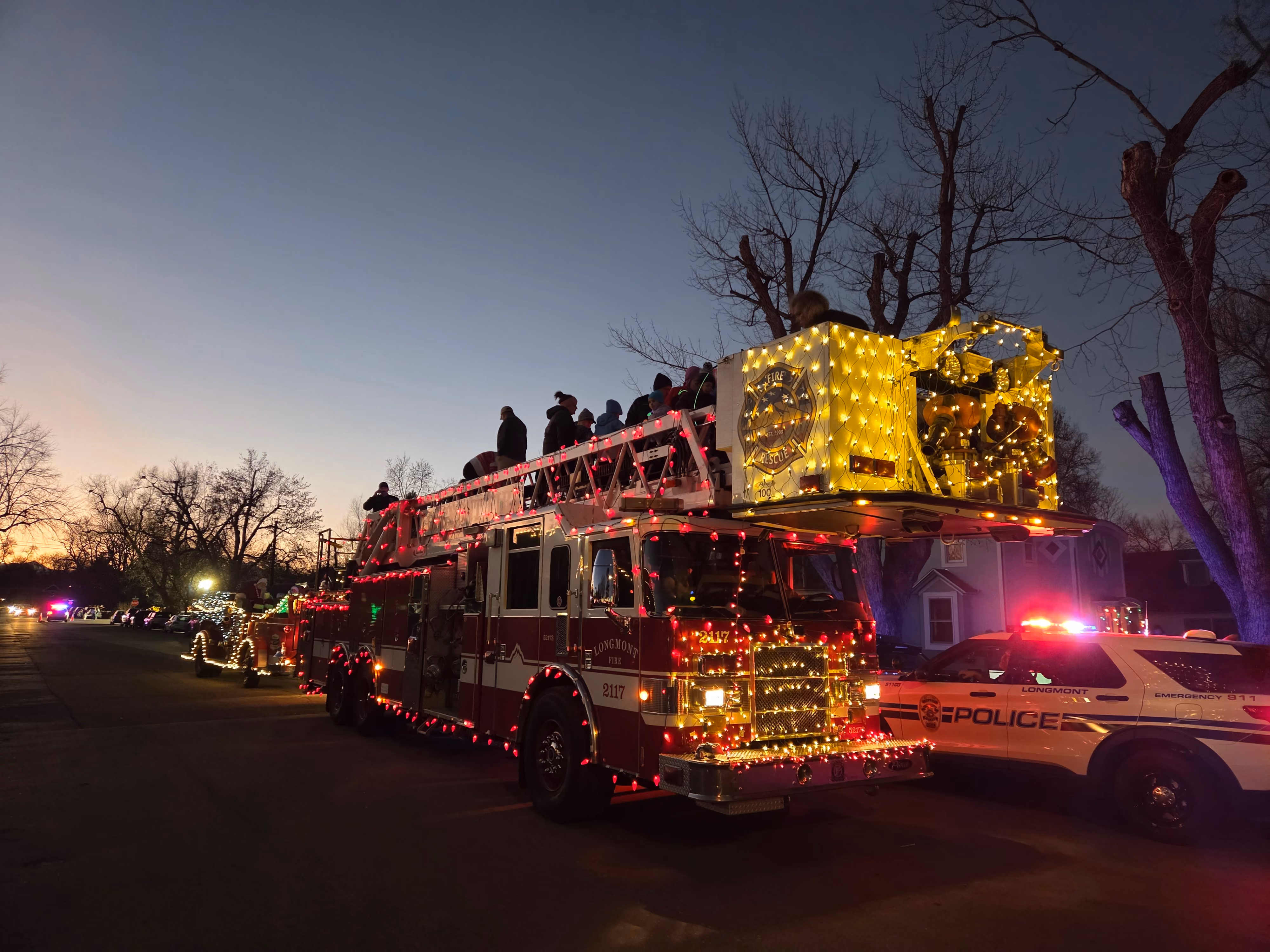 Longmont ladder truck decorated with holiday lights during the Longmont Lights Parade at dusk