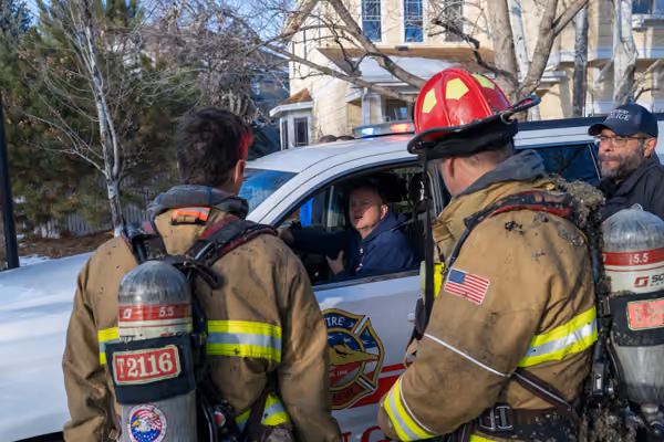 Firefighters in protective gear coordinating beside a vehicle at an emergency scene