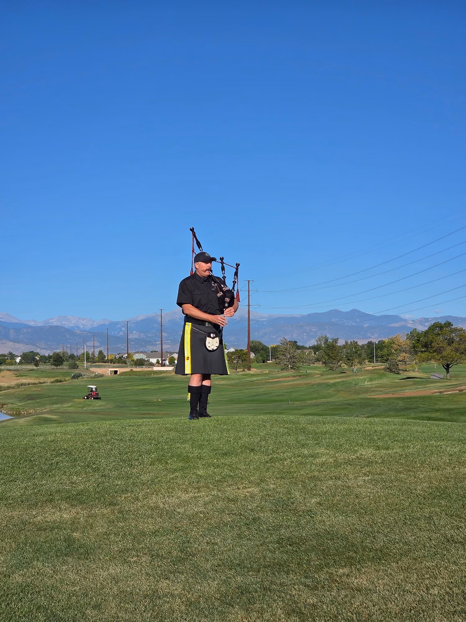 Bagpiper in a kilt playing on a golf course fairway