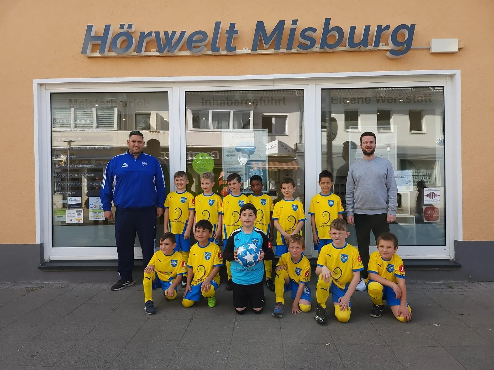 Jugendmannschaft des FC Stern Misburg in Hörwelt-Trikots vor dem Fachgeschäft in Misburg