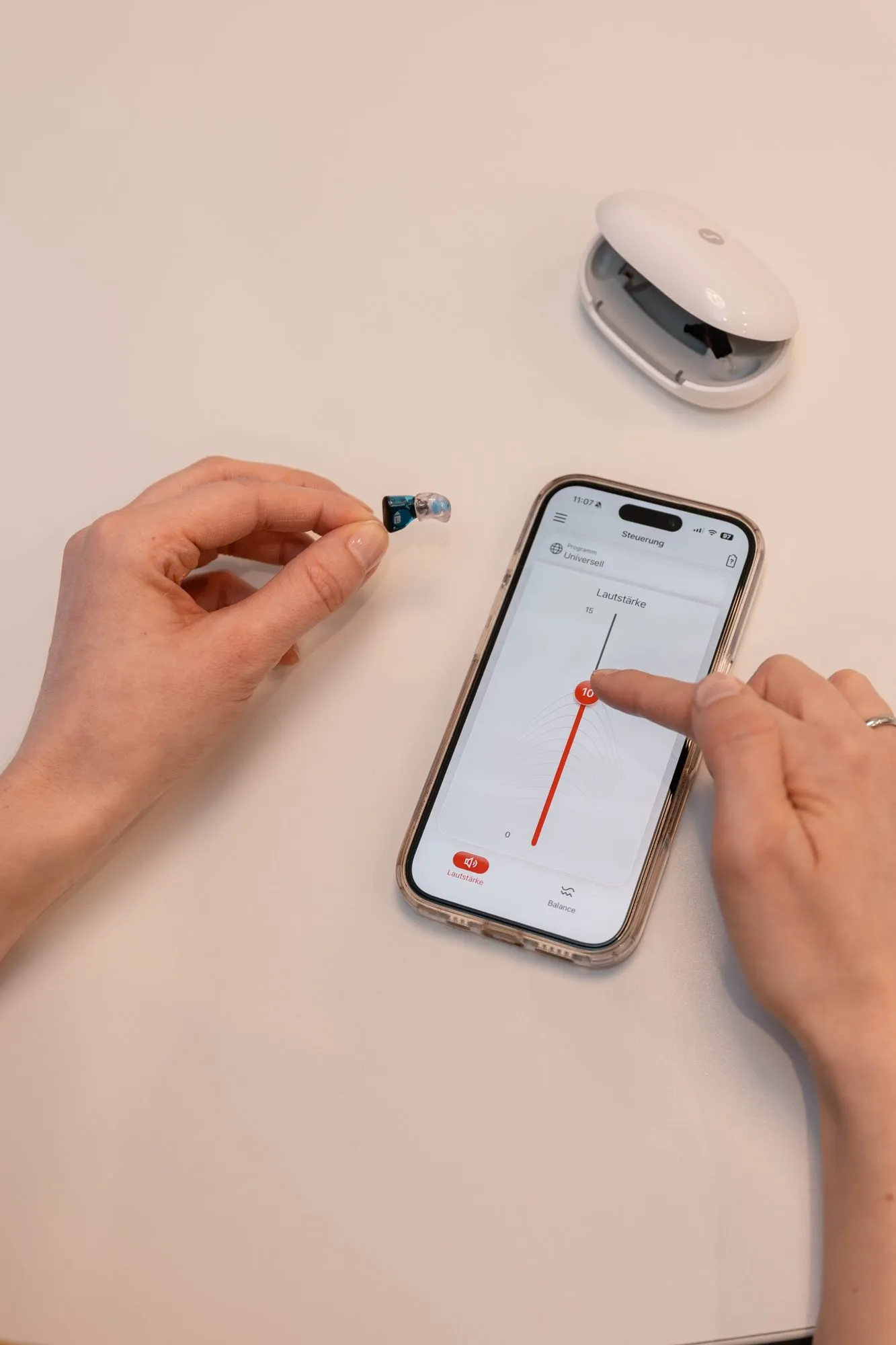 Im-Ohr-Hörgerät und Smartphone mit Hörgeräte-App