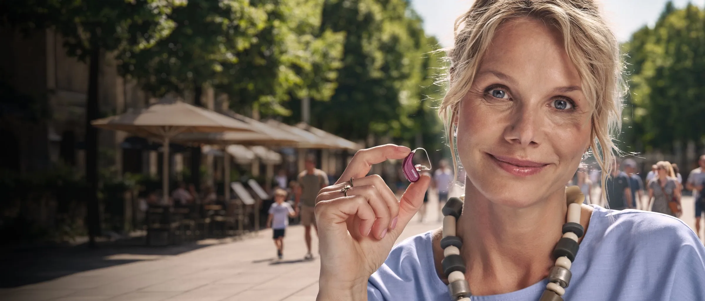 Frau hält ein Oticon-Reveal-Hörgerät in der Hand