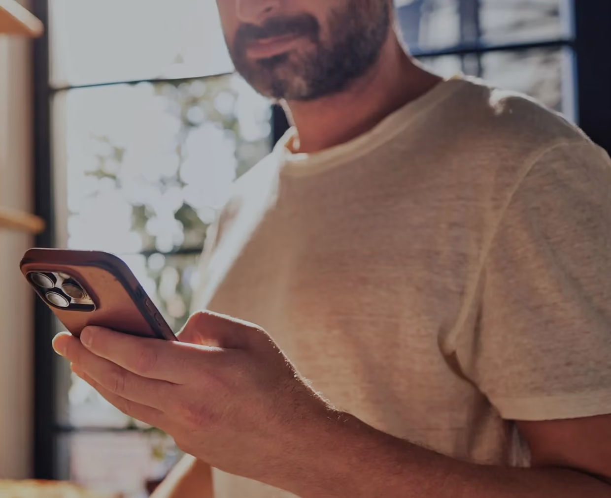 Man using a smartphone with PCI DSS, SOC 2, and HIPAA compliance certifications displayed.