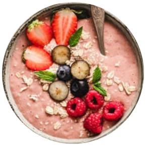 Bol de smoothie rose décoré avec des fraises tranchées, des myrtilles, des framboises, des feuilles de menthe et des flocons d'avoine, accompagné d'une cuillère métal.