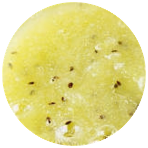 Gros plan d'une tranche de kiwi jaune montrant la texture juteuse et les petites graines brunes dispersées.