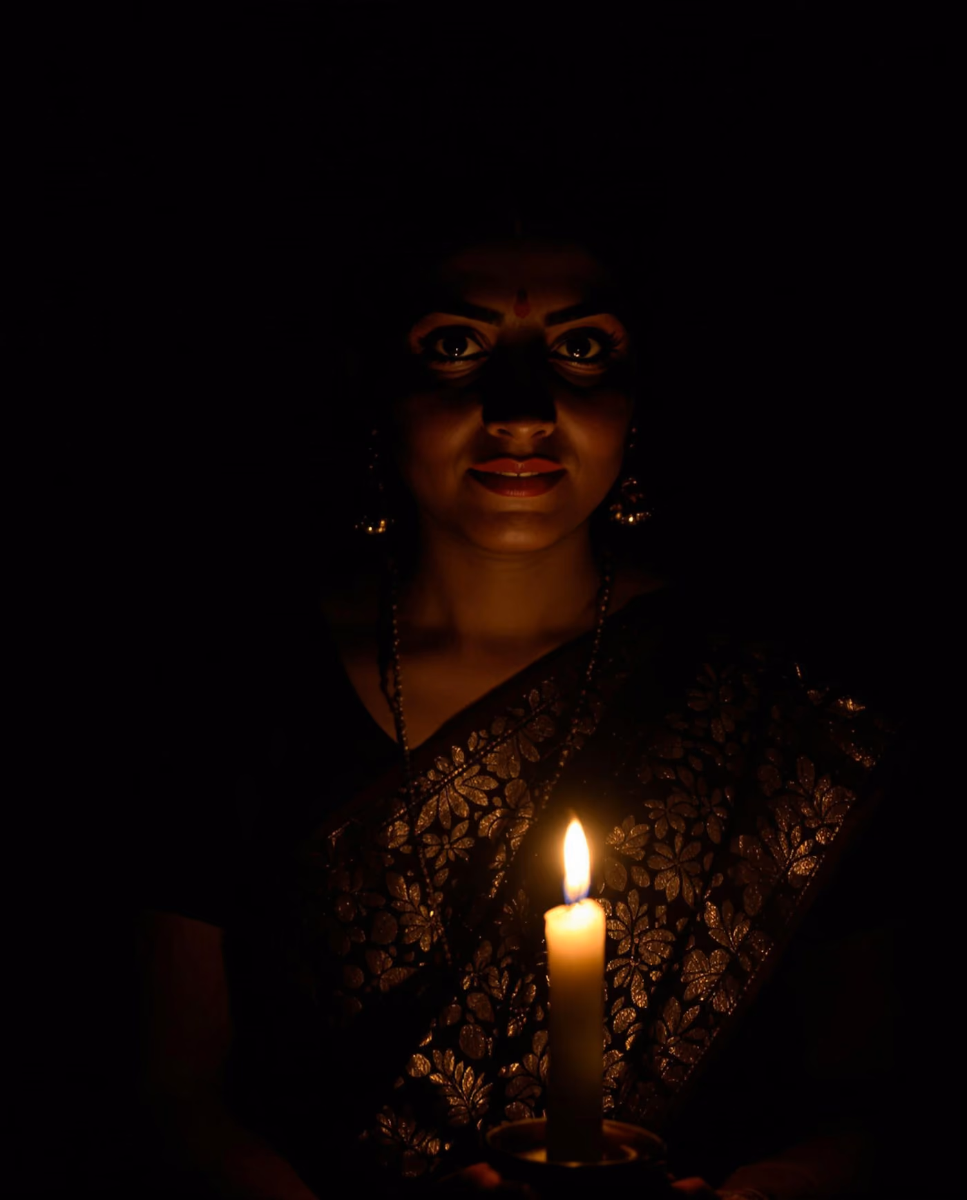 Woman in a dark room lit only by a candle
