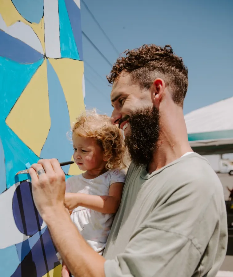 Two Love Has No Limits volunteers smiling painting a wall mural
