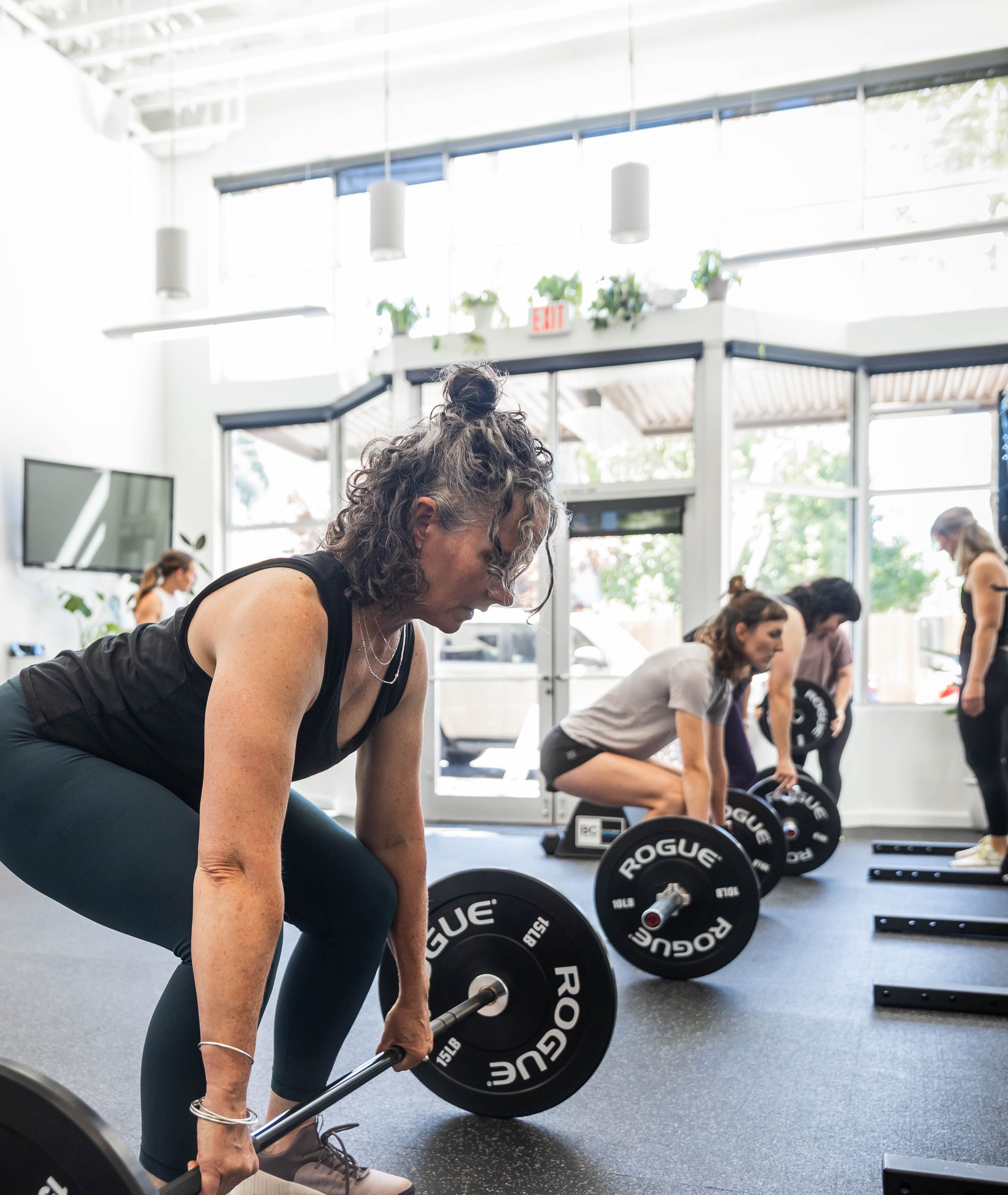 Women lifting barbells together in a bright gym at Women's Strength Collective in Portland, OR