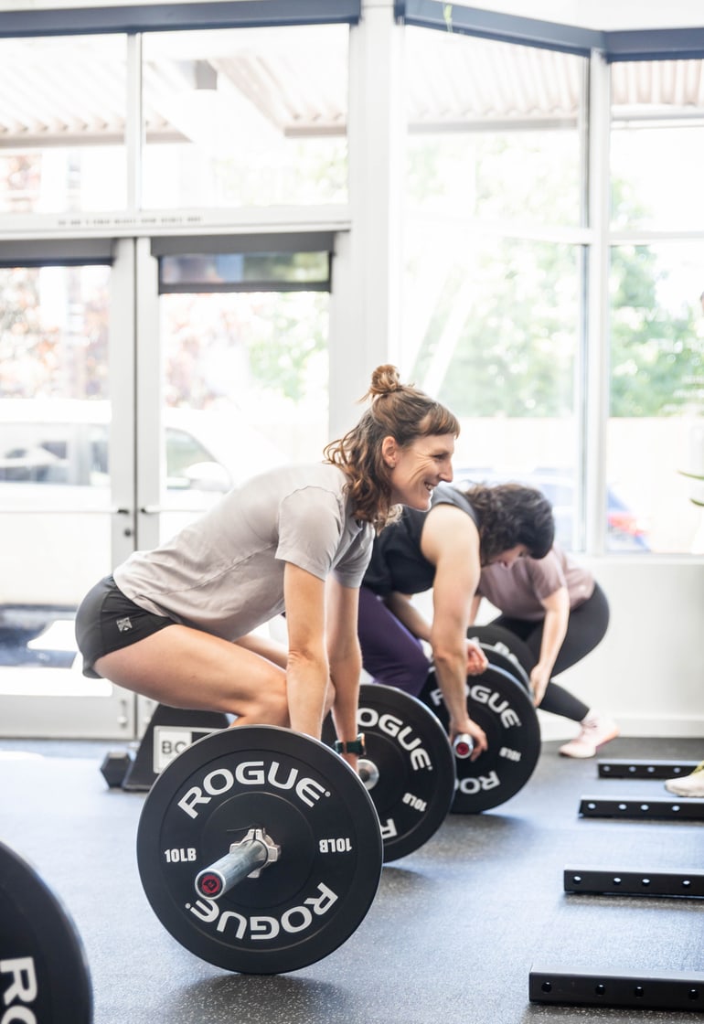 Members setting up for a deadlift with loaded barbells
