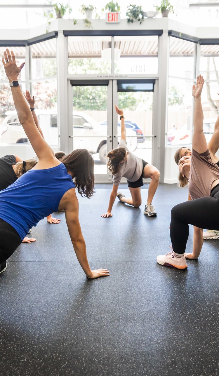 Women in a side lunge stretch on the open training floor at Women's Strength Collective