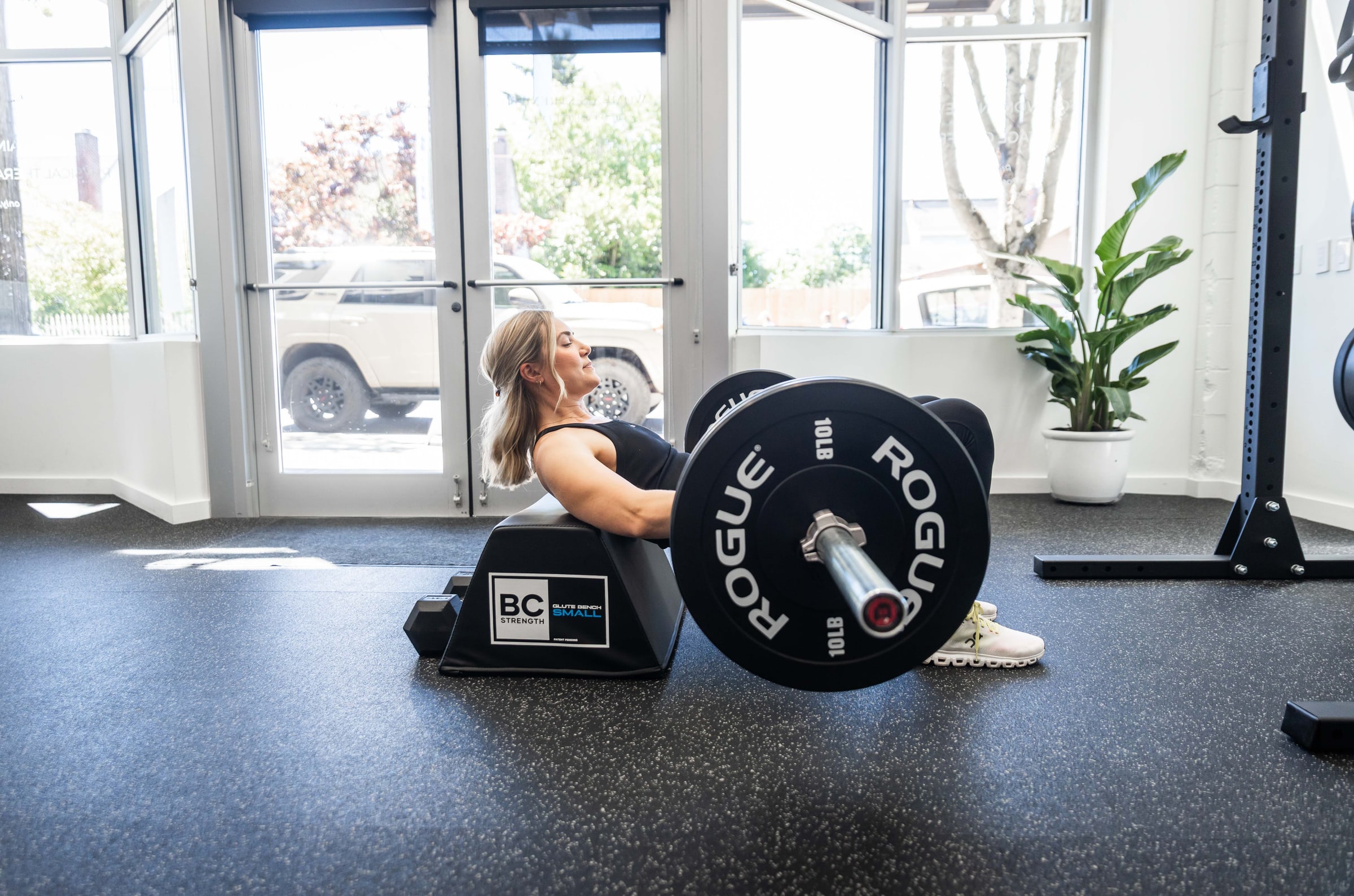 Woman doing a barbell hip thrust on a glute bench at Women's Strength Collective