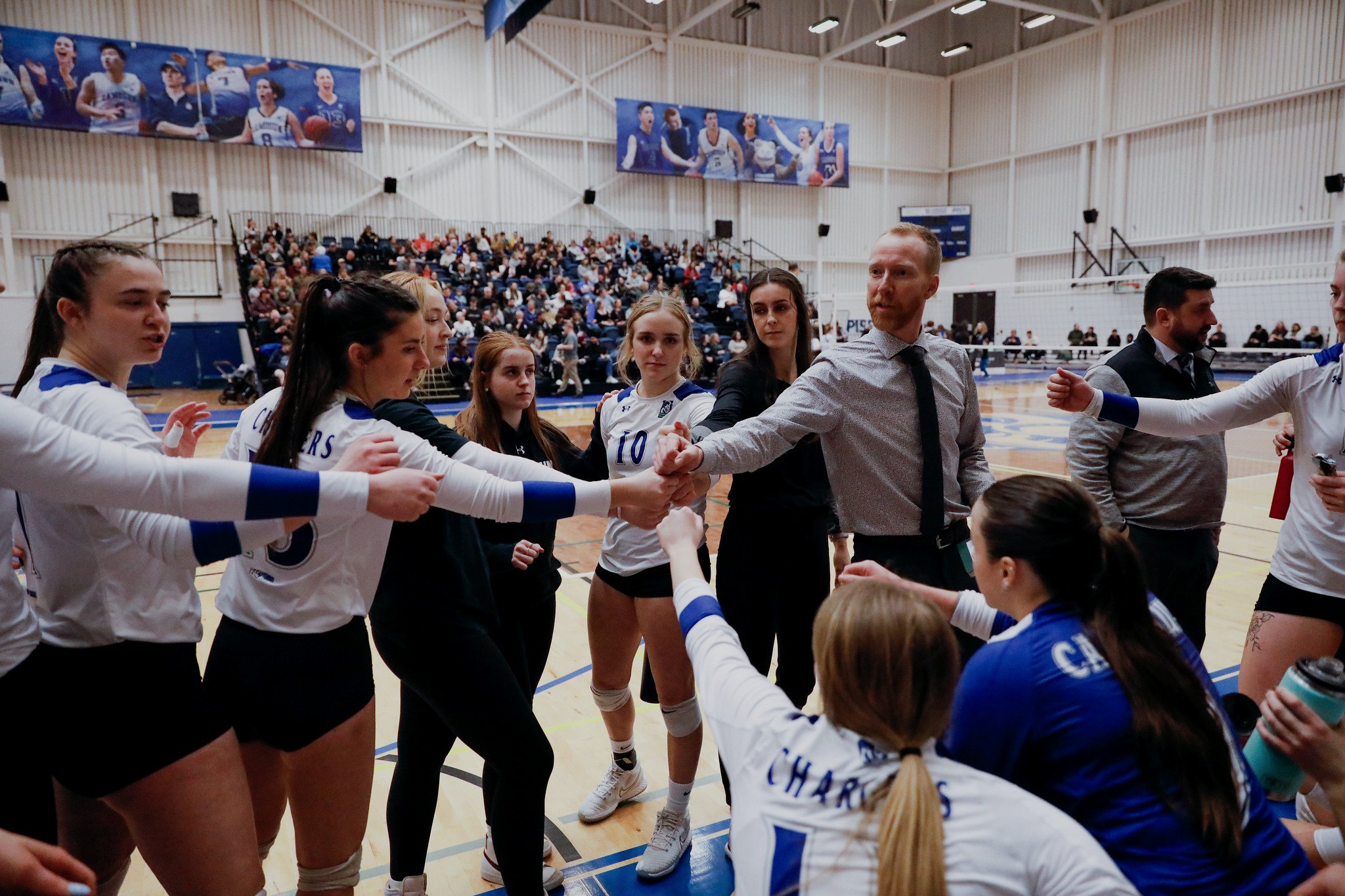 Brent and Camosun Chargers players bringing their hands in during a huddle
