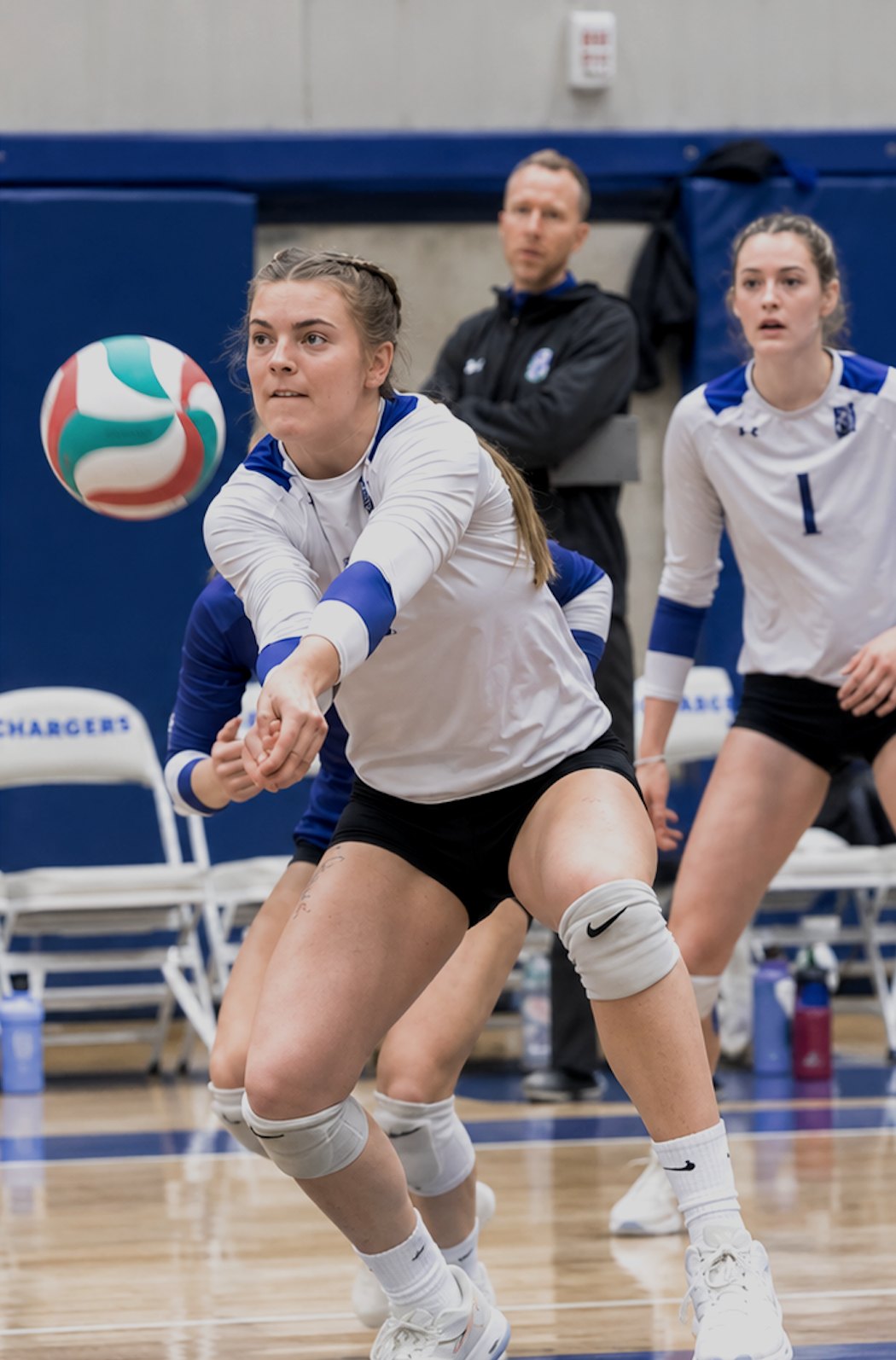 Camosun player passing the ball while Brent watches from the sideline