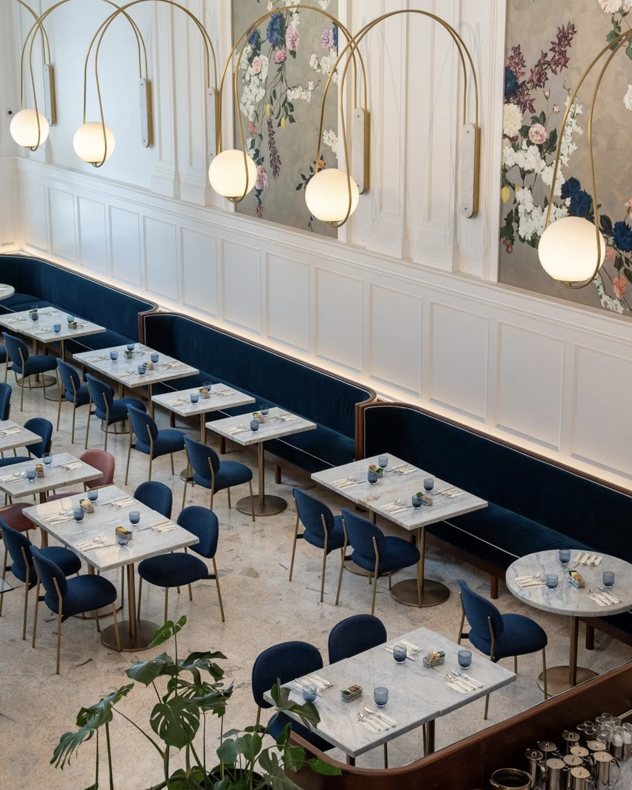 Elevated view of The Banque grand café in Hudson, NY, featuring custom palladiana terrazzo flooring, brass pendant lighting, and elegant blue upholstered seating.
