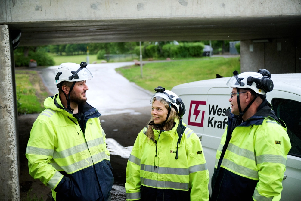 Tre yrkesarbetare i varselkläder som för ett samtal.