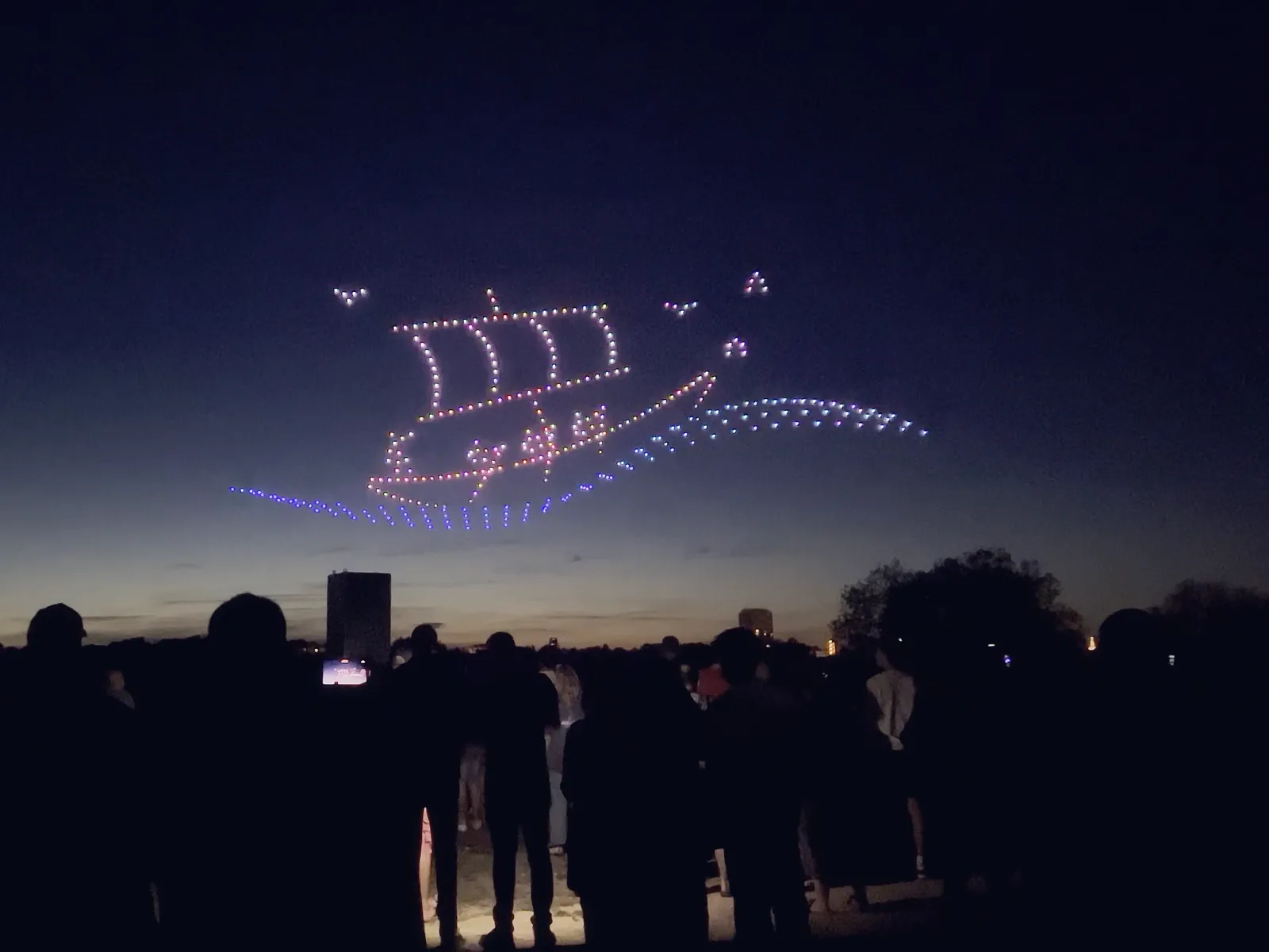 Spectacle de drones Le Secret des profondeurs : un navire lumineux au-dessus du public au crépuscule