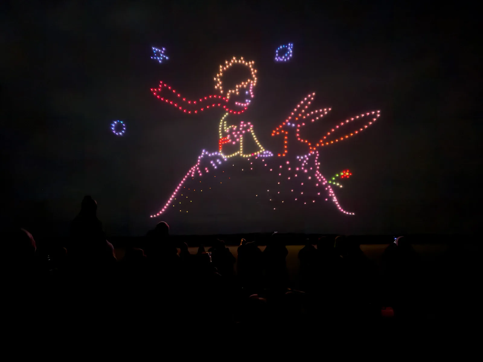 Spectacle de drones Le Petit Prince : le Petit Prince sur sa planète, écharpe au vent, dessiné par les drones au-dessus du public