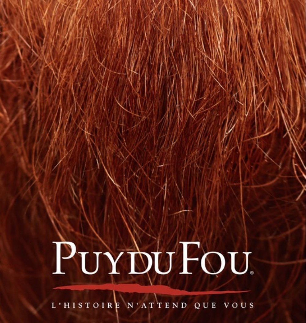 Puy du Fou : une chevelure rousse en très gros plan, le logo et la signature « L’histoire n’attend que vous »