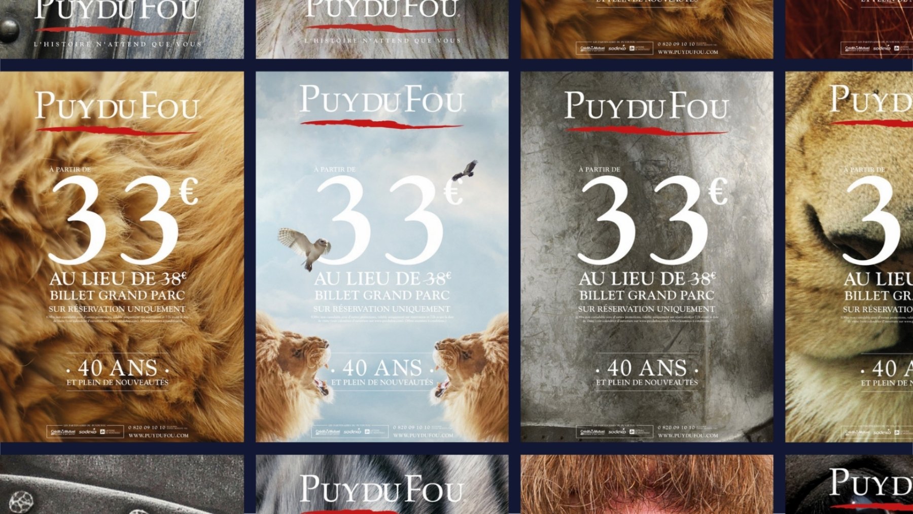 Puy du Fou, 40 ans : un mur d’affiches, dont les formats tactiques « À partir de 33 € au lieu de 38 €, billet Grand Parc » sur une crinière, un ciel où volent une chouette et un rapace au-dessus de deux lions, un métal patiné et un mufle de lion