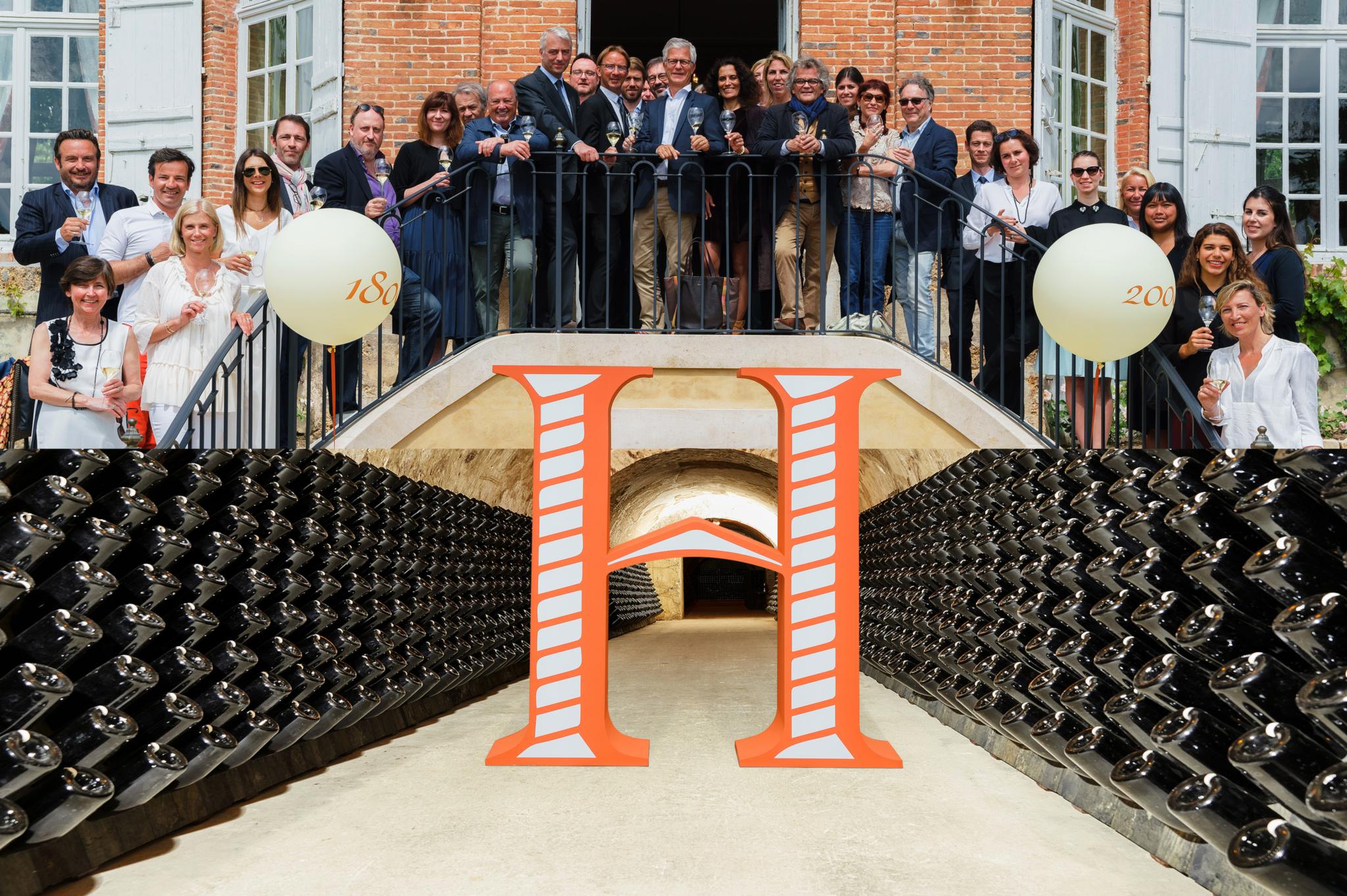 Champagne Henriot : le monogramme H dressé dans les caves entre les bouteilles, l’équipe de la maison au balcon