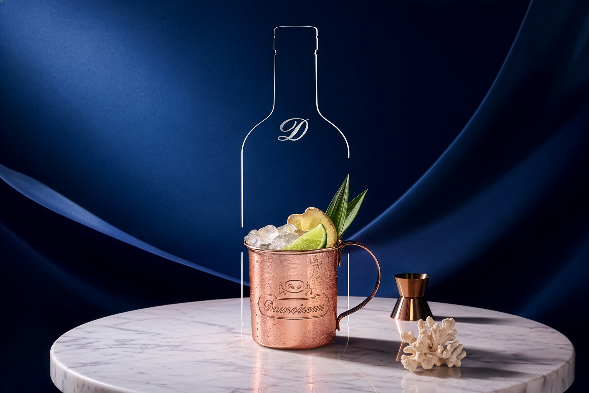 Damoiseau : un cocktail servi dans une tasse en cuivre gravée du logo, glace pilée, citron vert et gingembre, dans la silhouette d’une bouteille tracée d’un trait blanc, sur fond bleu nuit