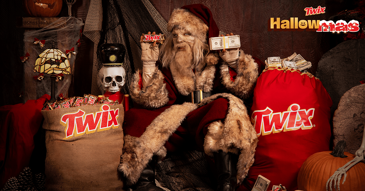 Un Père Noël zombie au visage gris, entouré de sacs Twix et de citrouilles, tient une barre Twix et une liasse de billets