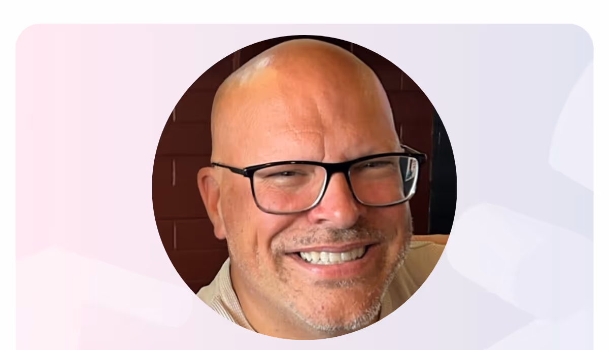 Smiling bald man with glasses and light facial hair in a circular frame.