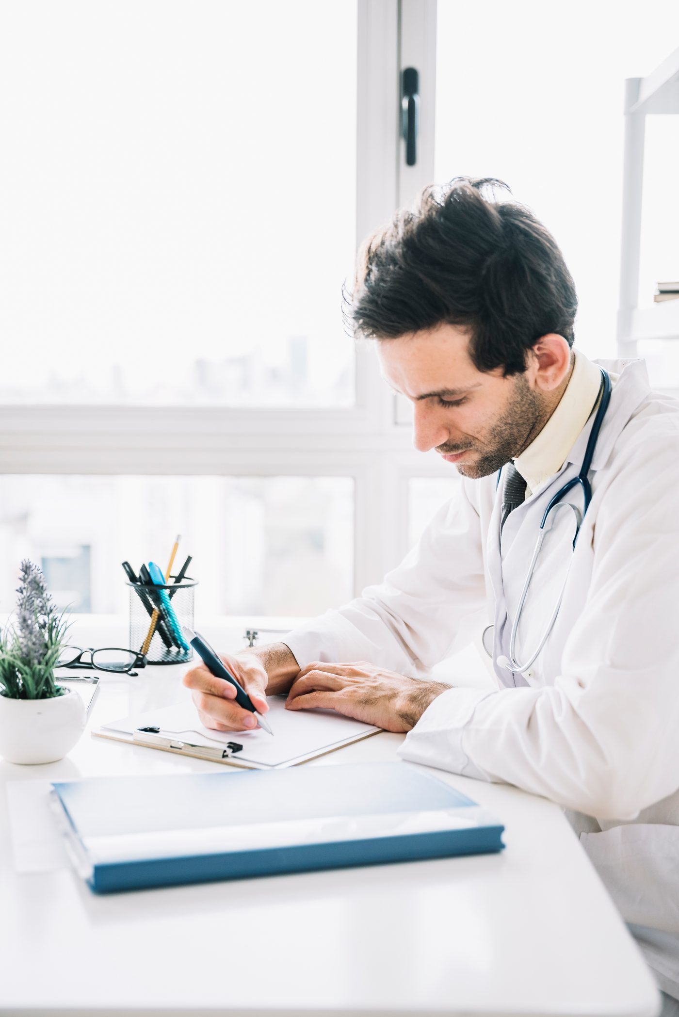 A doctor writing on a clipboard in a clinic