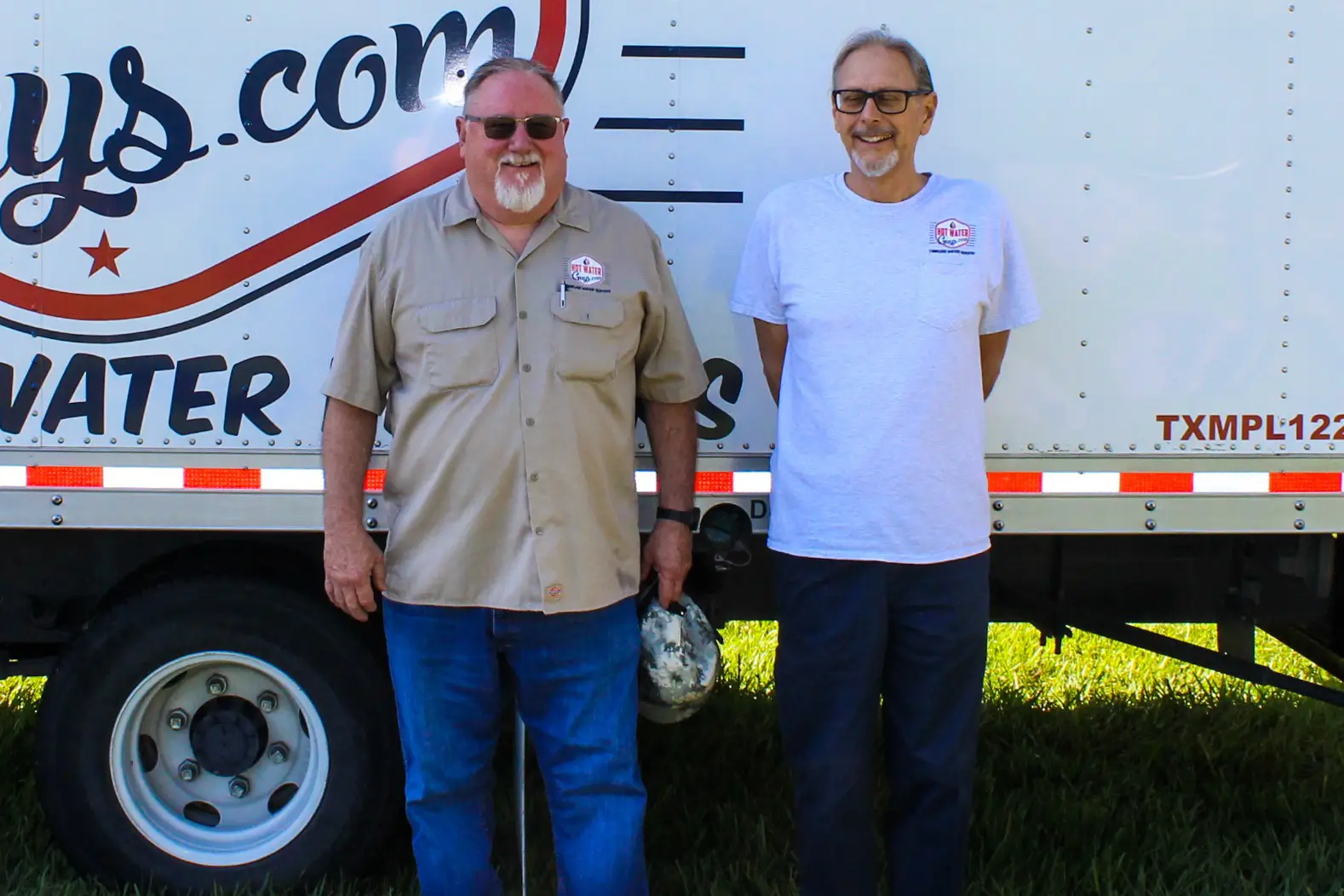 Hot Water Guys founders in front of a branded service truck