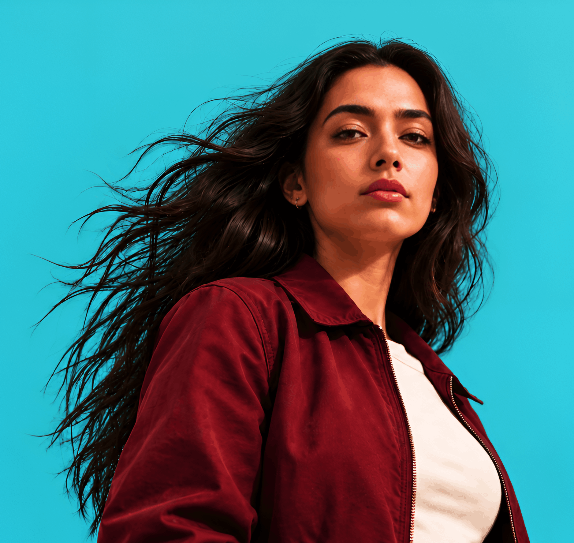 Woman with long dark hair in a red jacket against a blue sky