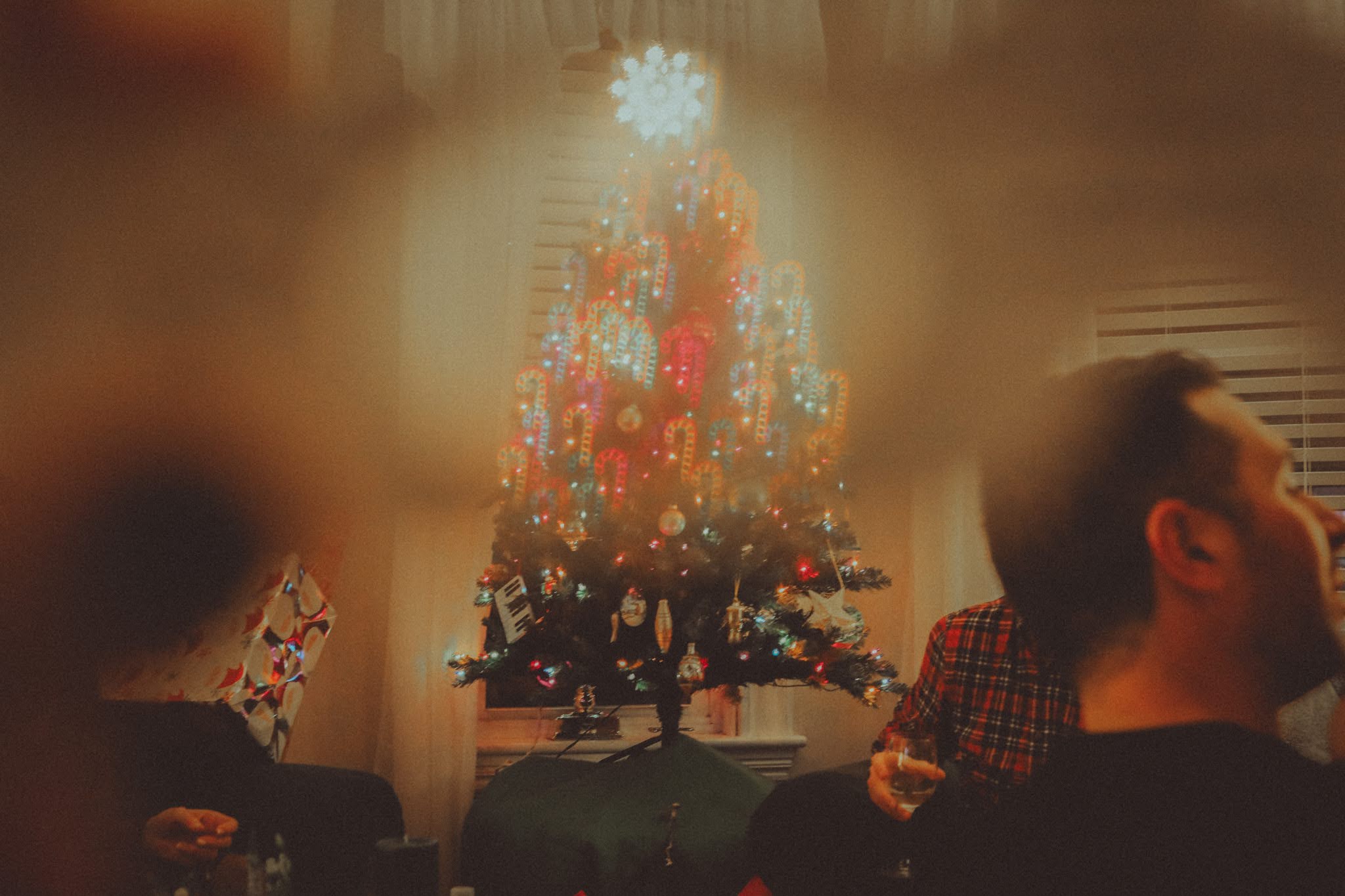 The tree glows through a soft blur while the family talks around it