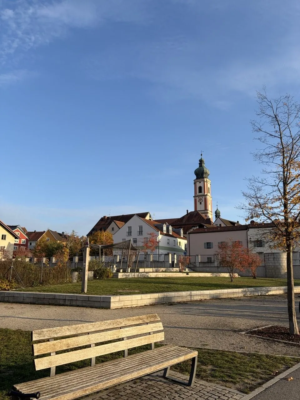Holzbank im Park am Regen vor der Rodinger Altstadt mit Kirchturm