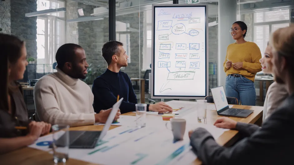 Team meeting around a whiteboard with a presenter.